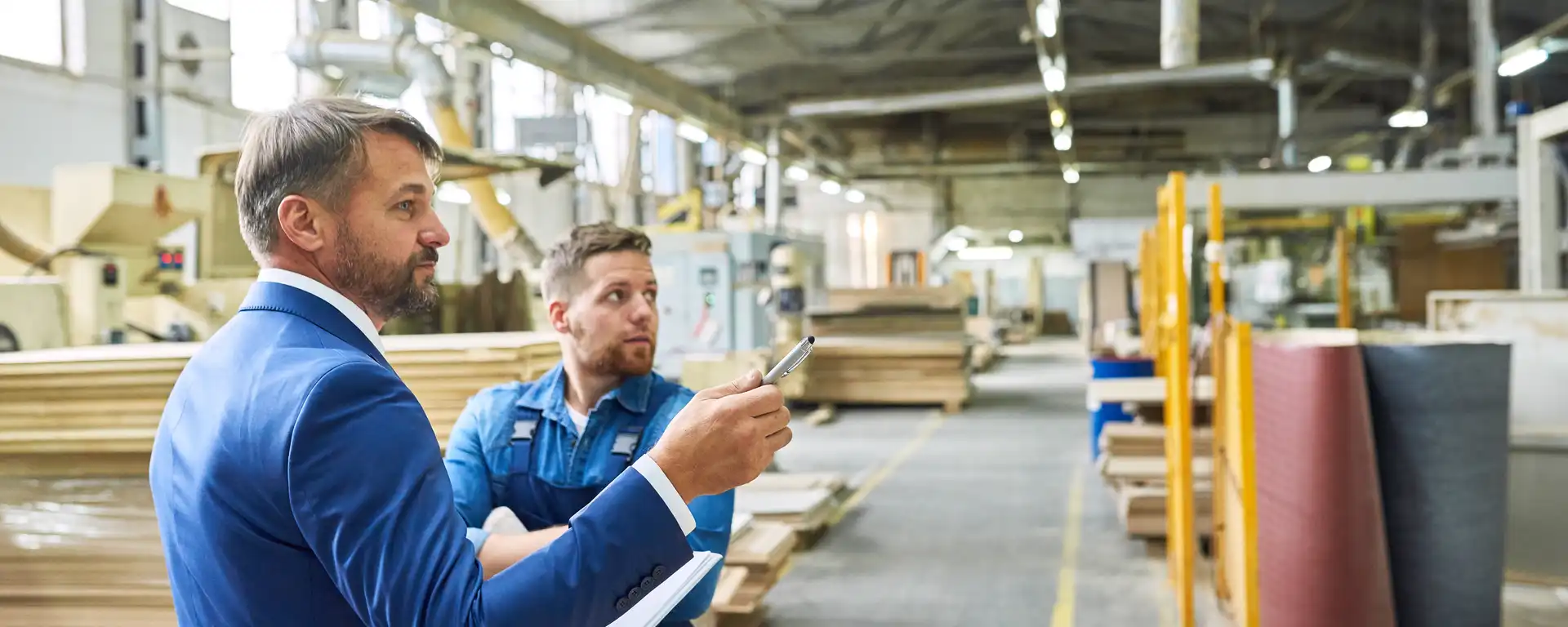 Zwei Männer stehen in einer großen Industriehalle