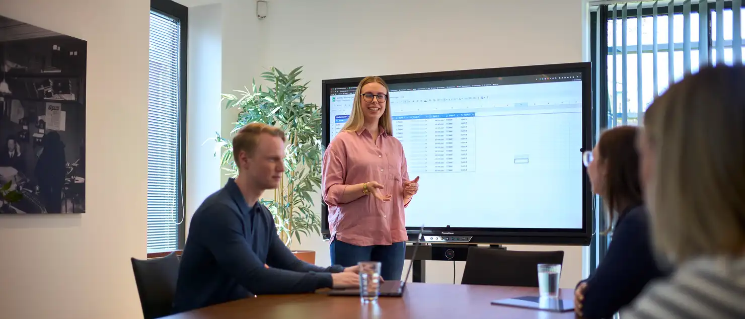 Eine Gruppe Menschen in einem Besprechungsraum vor einem großen Display